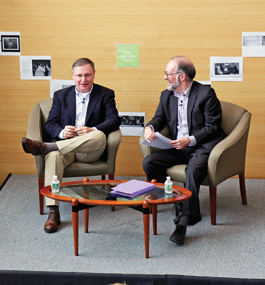 Chuck Rosenberg and Heller dean David Weil sit in armchairs, smiling and talking.
